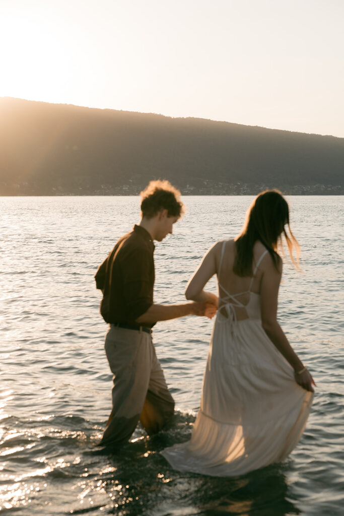 couple qui joue dans l'eau du lac face aux montagnes