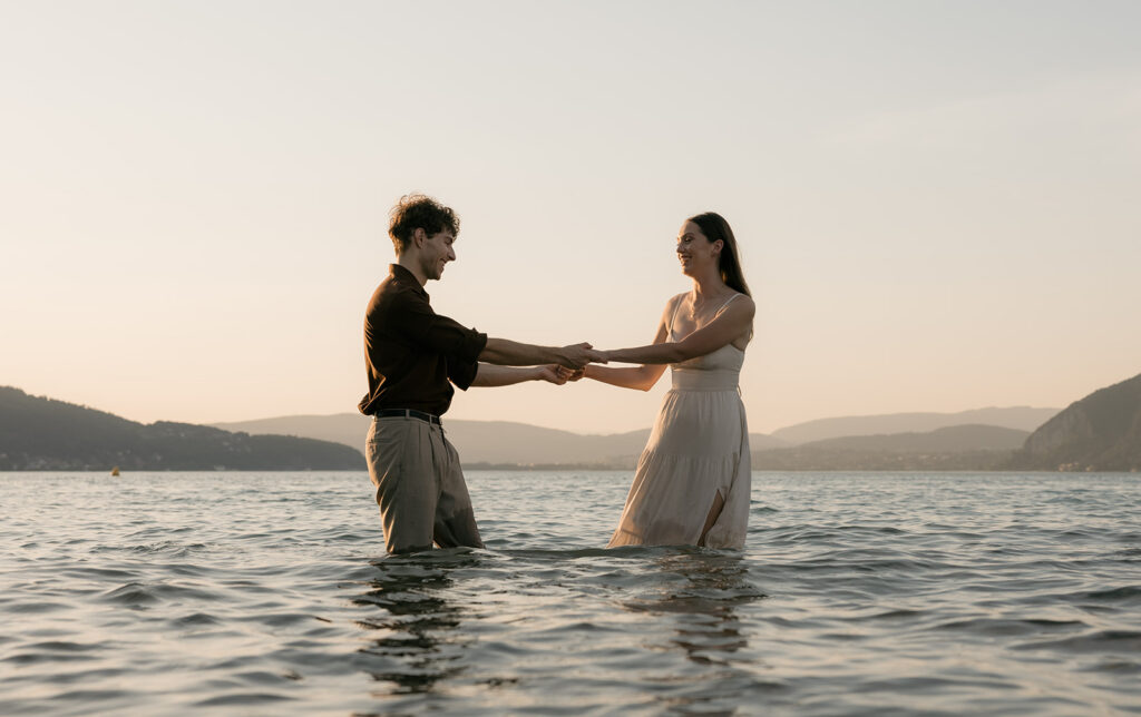 couple qui joue dans l'eau du lac face aux montagnes