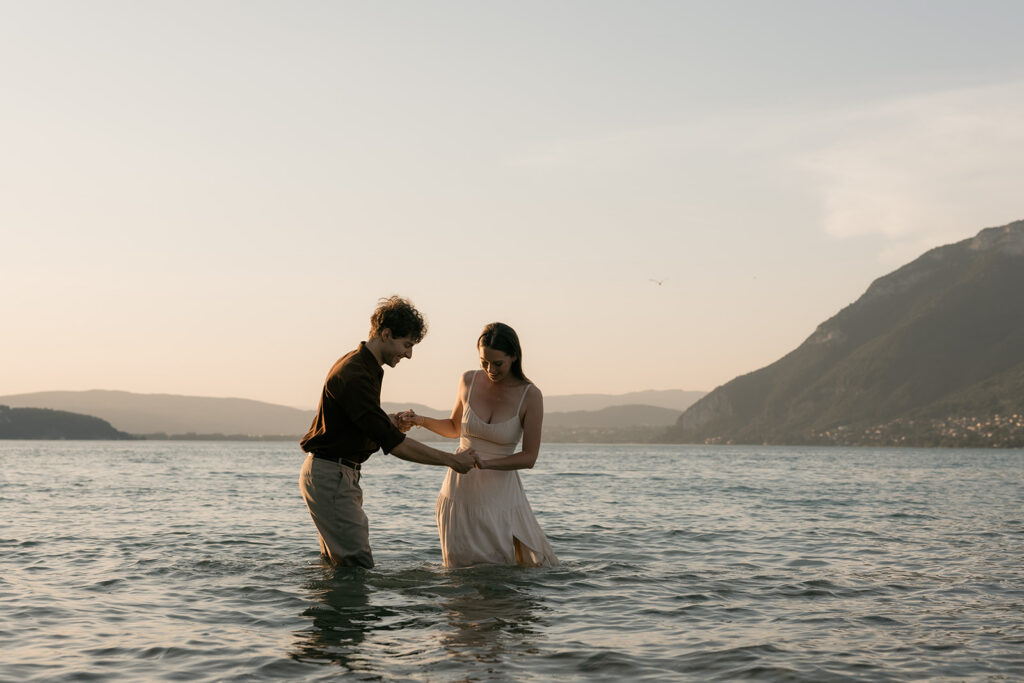 Couple de futurs mariés pieds dans l'eau avec vue sur le lac