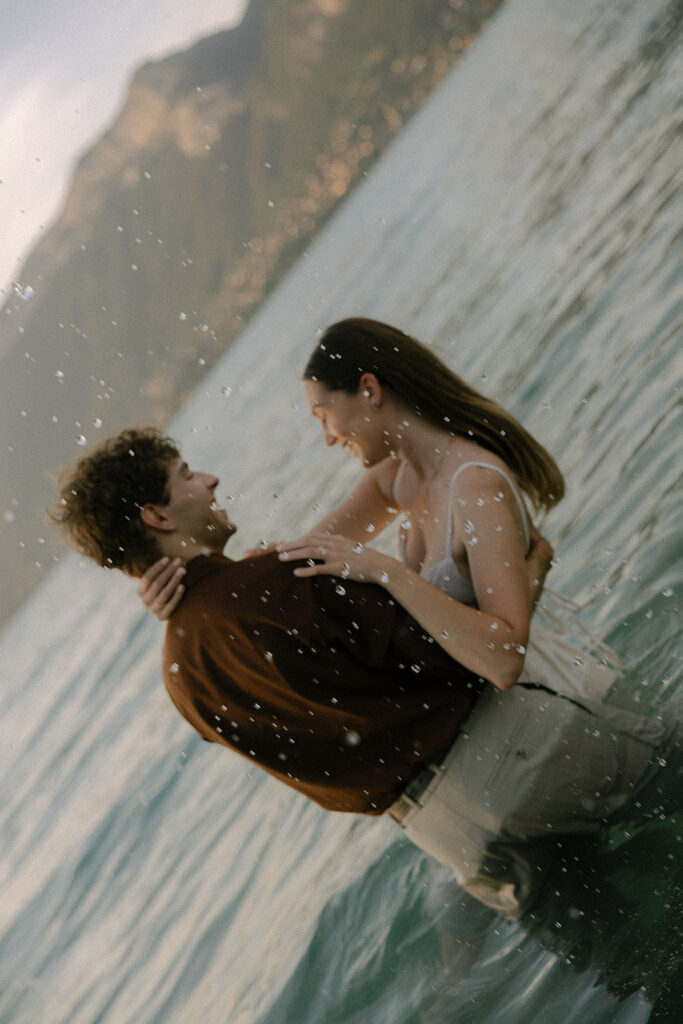 couple qui joue dans l'eau du lac face aux montagnes
